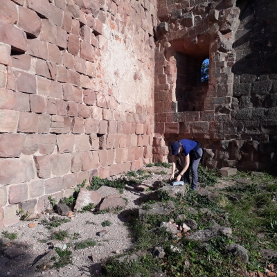 Des pierres montées en murs, une fenêtre dans un renfoncement et Marie penchée sur son matériel dentaire